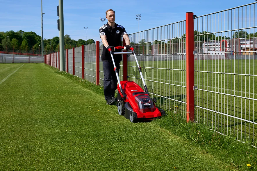 Person mäht Rasen mit Rasenmäher